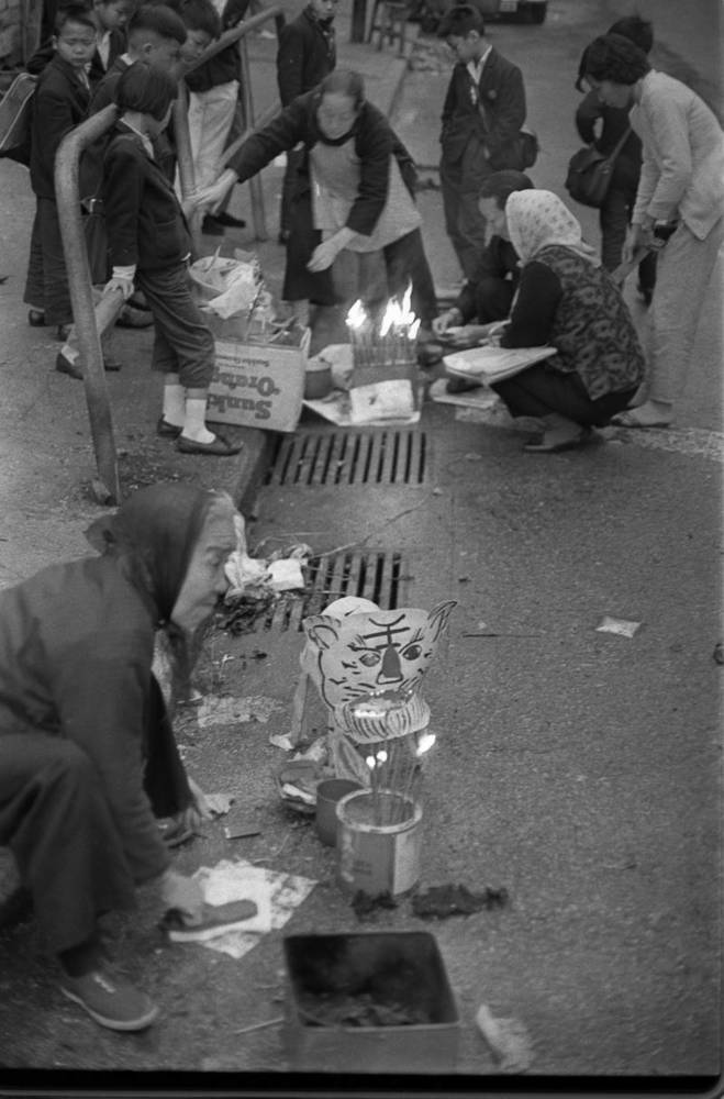 Worshippers beating paper men with their slippers to exorcise evil spirits on a streetside during the Feast of the Waking of Insects.