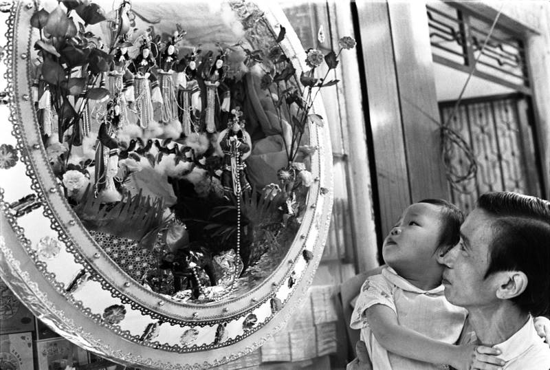 Father and daughter looking at a paper-made decoration for the celebration of traditional Seven Sisters Festival. The decoration is made to celebrate the traditional Seven Sisters Festivals, which falls on the seventh day of the seventh moon of the lunar year calendar.