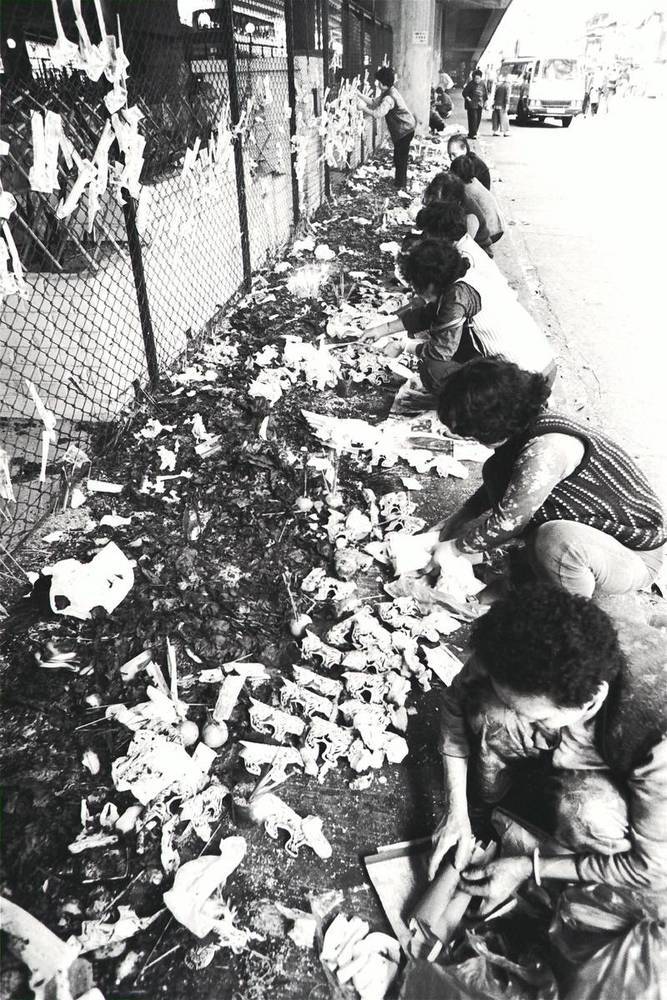 Women beating little paper men with shoes before a paper replica of the White Tiger on Stone Nullah Street, Wan Chai, in the hope of driving evil spirits and bad luck away. The White Tiger Festival is a traditional festival that falls on the second moon of the lunar calendar.